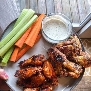 A plate of delicious parmesan garlic and buffalo wing with a side of creamy homemade Basil Ranch. On the side are sliced carrots and celery sticks. The recipe is listed below the picture.