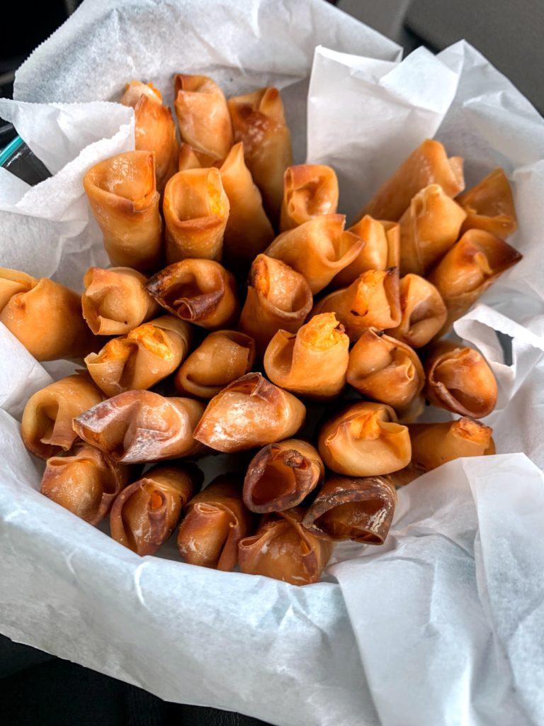 Partchment paper lined bowl with 40 individual skinny and crispy wonton wrapped baked buffalo chicken eggrolls. Not pictured is homemade ranch for dipping.