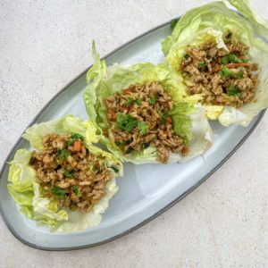 Three large lettuce cups filled with Thai chicken and topped with cilantro and green onion. This looks like a very light and healthy chicken recipe with Asian influence