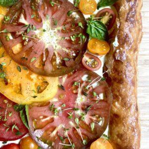 Puff pastry tart filled with fresh heirloom and cherry tomatoes, fresh basil, and microgreens, and a feta basil spread.