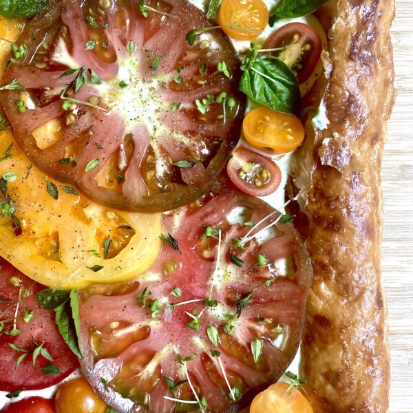 Puff pastry tart filled with fresh heirloom and cherry tomatoes, fresh basil, and microgreens, and a feta basil spread.